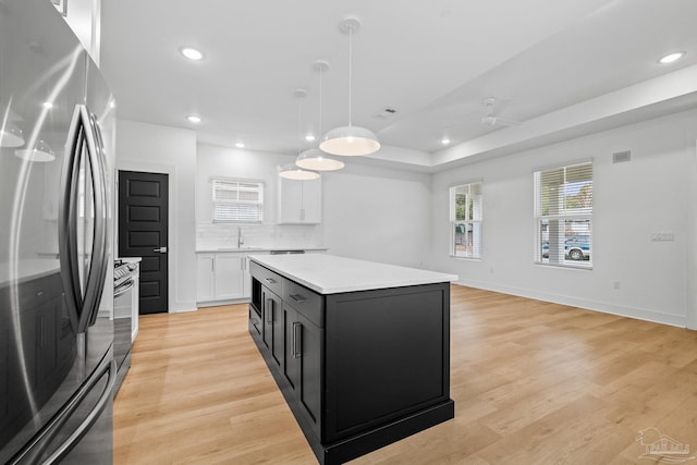 kitchen with white cabinetry, hanging light fixtures, a center island, light hardwood / wood-style floors, and stainless steel appliances