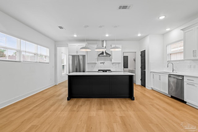 kitchen with sink, white cabinetry, a center island, hanging light fixtures, and stainless steel appliances