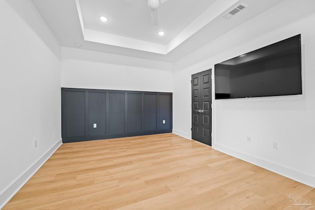 unfurnished bedroom featuring light hardwood / wood-style floors and a tray ceiling