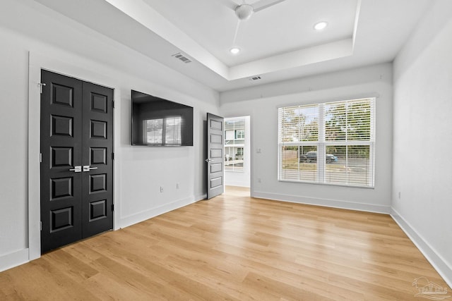 entrance foyer with a tray ceiling and light hardwood / wood-style floors