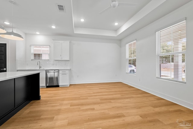 kitchen with pendant lighting, white cabinetry, decorative backsplash, stainless steel dishwasher, and light wood-type flooring