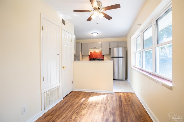 kitchen with dark hardwood / wood-style flooring, gray cabinets, stainless steel refrigerator, and tasteful backsplash