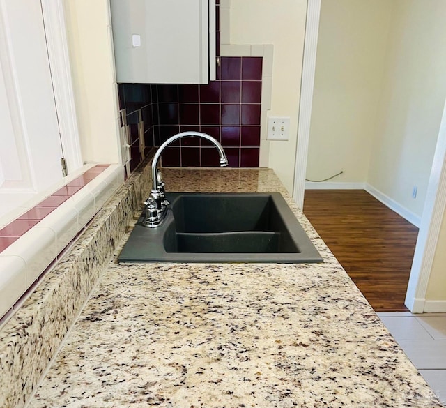 kitchen featuring light stone countertops, tasteful backsplash, sink, white cabinets, and hardwood / wood-style floors