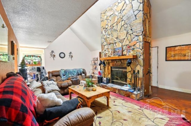 2738 Garcon Point Rd, Milton, FL 32583 - living room with vaulted ceiling, wood finished floors, baseboards, a fireplace, and a textured ceiling