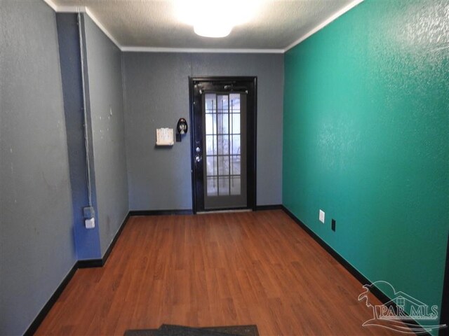 unfurnished room featuring wood-type flooring, a textured ceiling, and ornamental molding