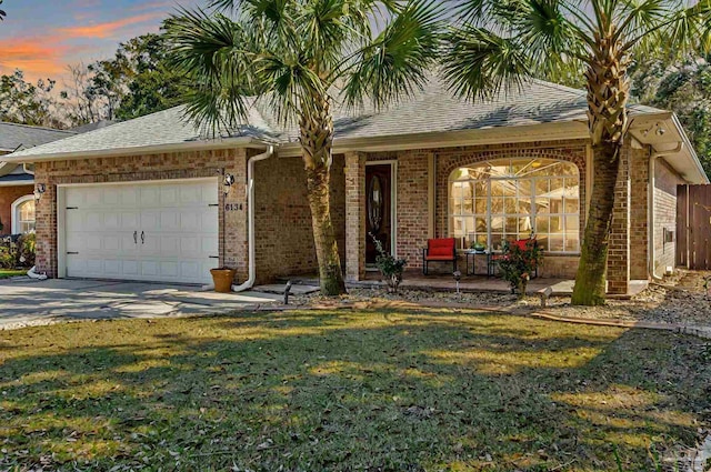 ranch-style house with an attached garage, brick siding, concrete driveway, roof with shingles, and a front yard