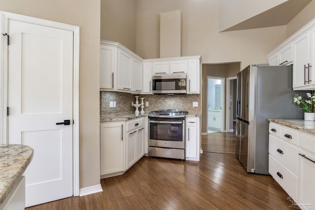 kitchen with white cabinetry, appliances with stainless steel finishes, decorative backsplash, and dark wood-type flooring