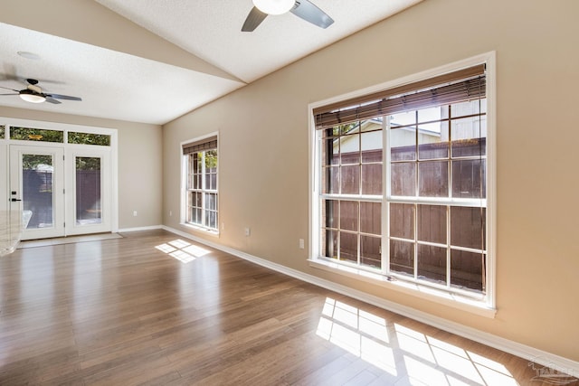 empty room featuring lofted ceiling, a ceiling fan, a textured ceiling, wood finished floors, and baseboards