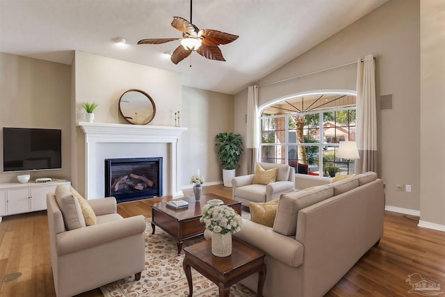 living room with lofted ceiling, ceiling fan, a tile fireplace, and wood finished floors