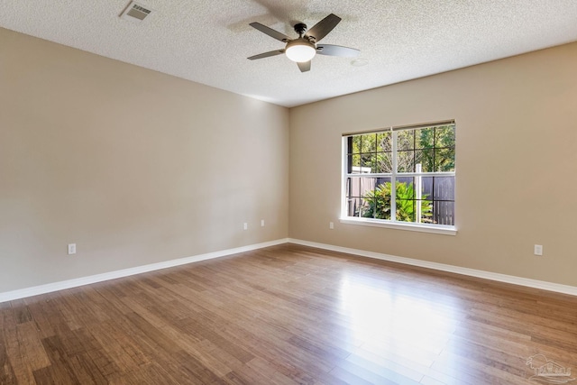 spare room with a ceiling fan, visible vents, baseboards, and wood finished floors