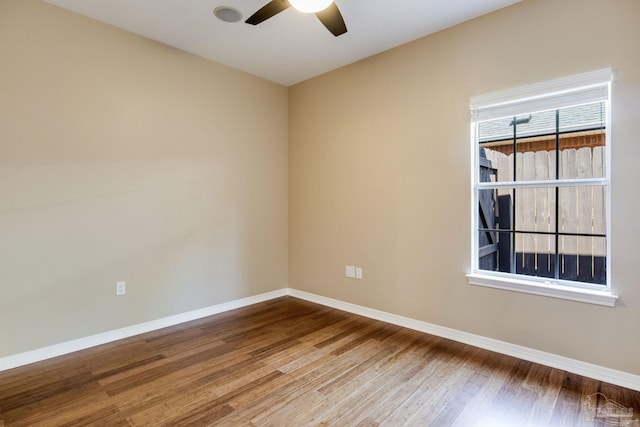 empty room featuring ceiling fan, baseboards, and wood finished floors