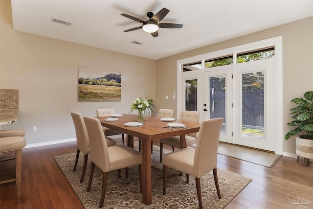 dining space with wood finished floors, visible vents, and baseboards