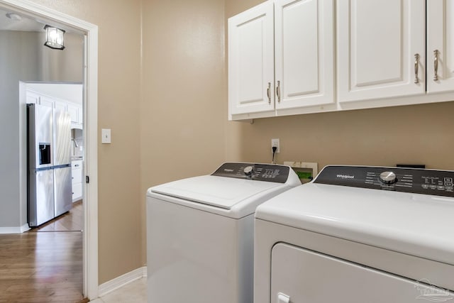 laundry room featuring light wood-type flooring, washing machine and clothes dryer, cabinet space, and baseboards