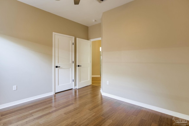 unfurnished room with visible vents, wood finished floors, a ceiling fan, and baseboards