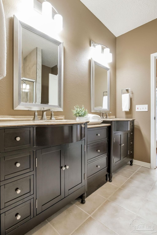 bathroom with a stall shower, baseboards, tile patterned floors, a textured ceiling, and vanity