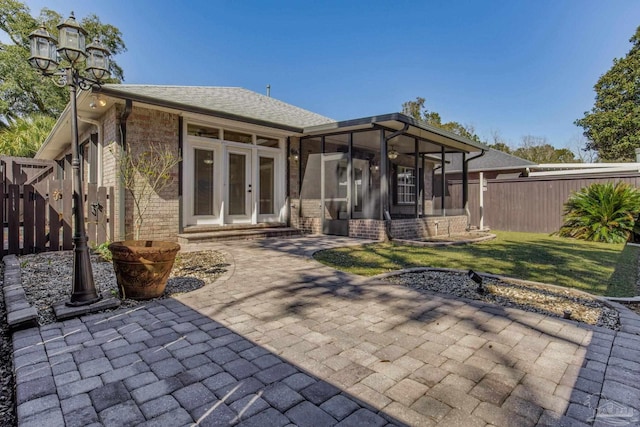 back of property with french doors, brick siding, a patio, a sunroom, and fence