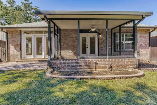 back of property featuring a sunroom, brick siding, a lawn, and french doors