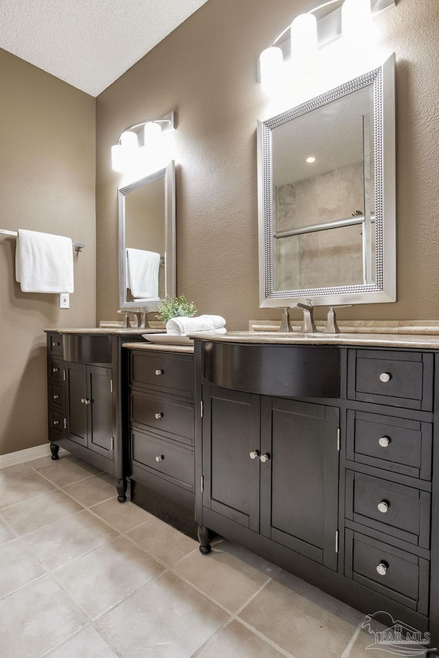 bathroom featuring a textured ceiling, a stall shower, tile patterned flooring, and vanity