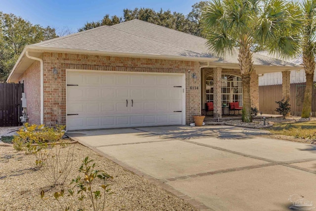 ranch-style home with a shingled roof, brick siding, fence, and an attached garage