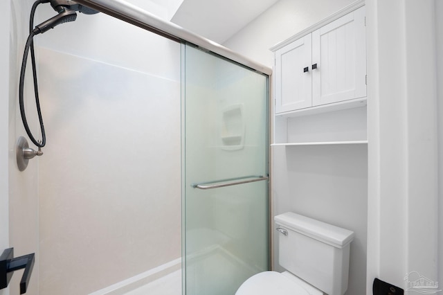 bathroom featuring toilet and a shower with shower door