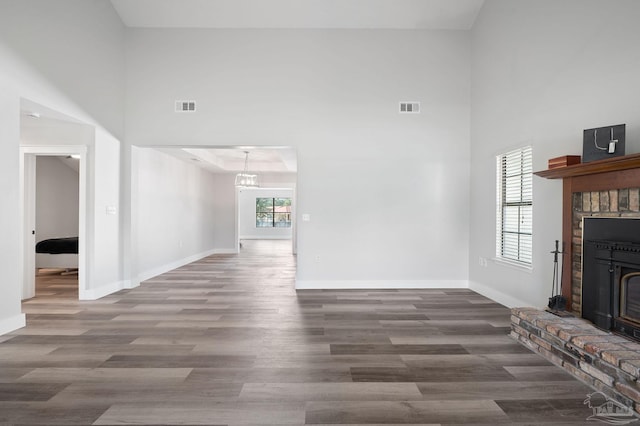 unfurnished living room featuring dark hardwood / wood-style flooring, a fireplace, a wealth of natural light, and a high ceiling