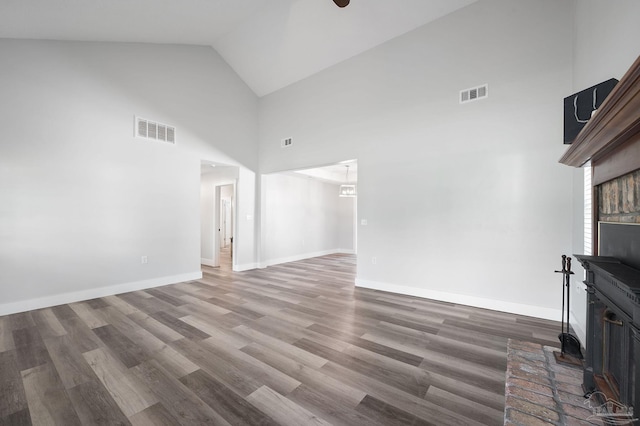 unfurnished living room with wood-type flooring, high vaulted ceiling, ceiling fan, and a brick fireplace