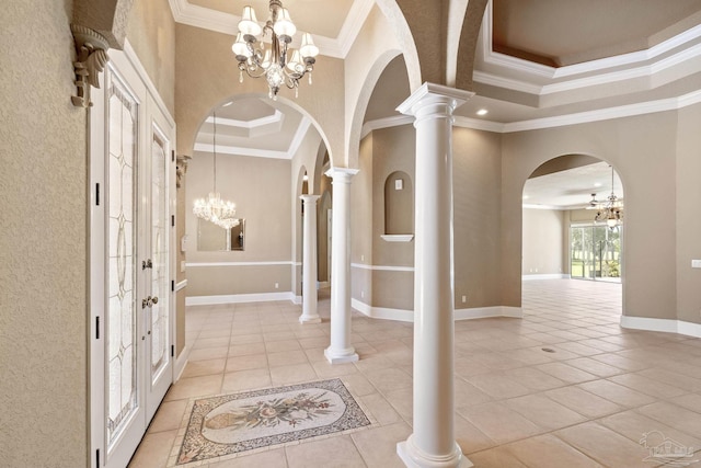 foyer entrance with a chandelier, crown molding, arched walkways, light tile patterned flooring, and baseboards