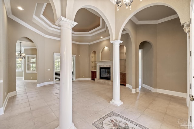 unfurnished living room with crown molding, a glass covered fireplace, light tile patterned flooring, a chandelier, and baseboards