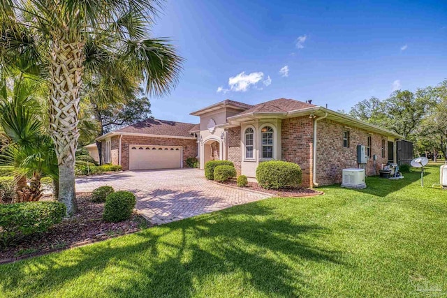 mediterranean / spanish-style house with brick siding, driveway, an attached garage, and a front lawn
