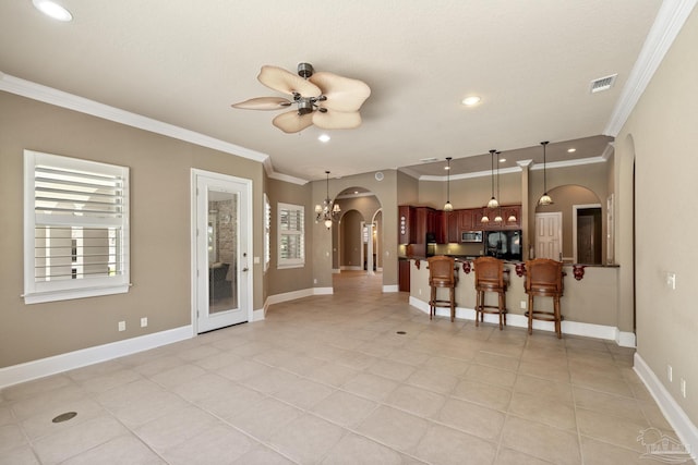 kitchen with arched walkways, ornamental molding, stainless steel microwave, ceiling fan, and a kitchen bar