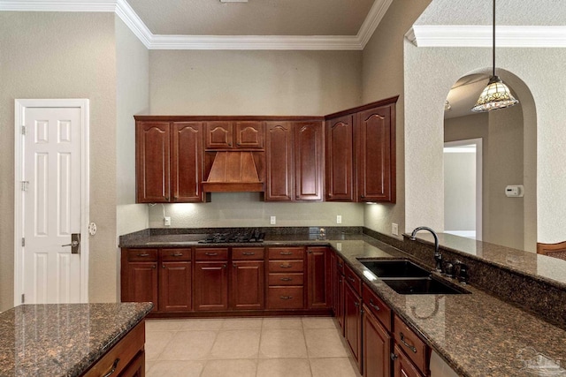 kitchen with premium range hood, a sink, ornamental molding, arched walkways, and dark stone counters