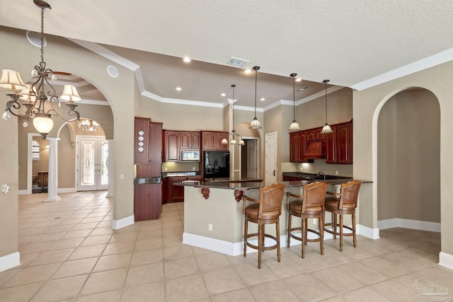 kitchen featuring arched walkways, black fridge, decorative columns, a peninsula, and dark countertops
