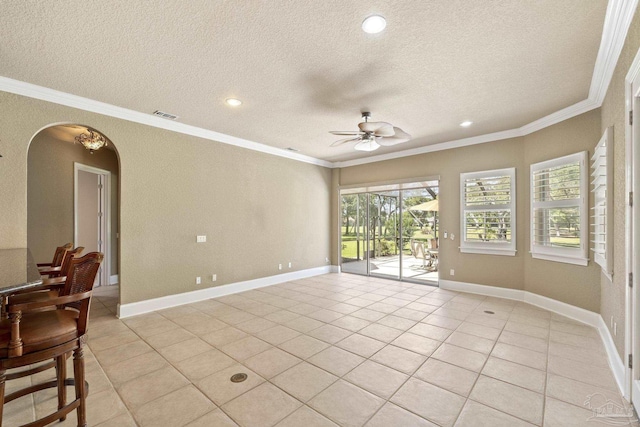 spare room featuring arched walkways, a textured ceiling, ornamental molding, a ceiling fan, and light tile patterned floors