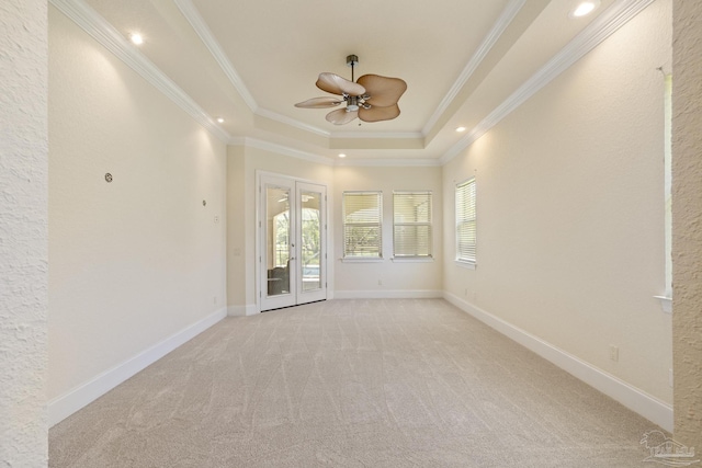 unfurnished room featuring french doors, a ceiling fan, light carpet, a raised ceiling, and ornamental molding