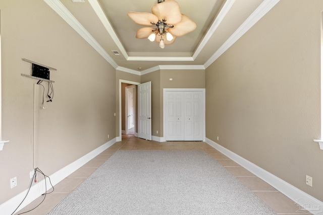 unfurnished bedroom featuring light tile patterned flooring, a raised ceiling, ornamental molding, ceiling fan, and baseboards