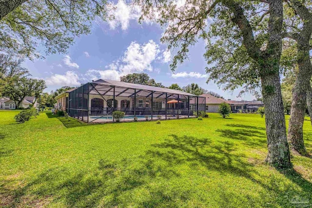 view of grassy yard featuring an outdoor pool and a lanai