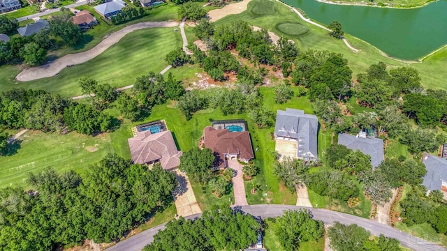 view of property location featuring a nearby body of water, nearby suburban area, and a local golf course