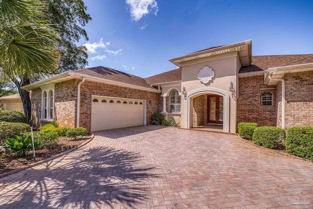 view of front facade with a garage, decorative driveway, brick siding, and a shingled roof