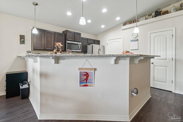 kitchen with a kitchen bar, pendant lighting, vaulted ceiling, and appliances with stainless steel finishes