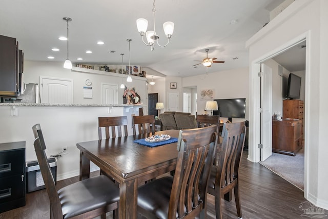 dining space with vaulted ceiling, ceiling fan with notable chandelier, and dark hardwood / wood-style flooring