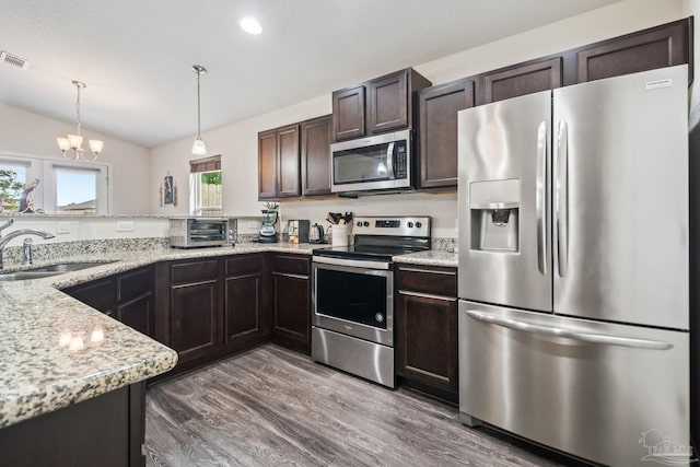 kitchen with appliances with stainless steel finishes, a chandelier, sink, lofted ceiling, and dark wood-type flooring