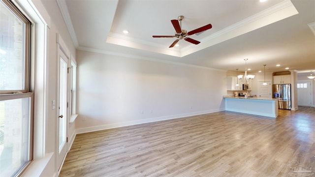 720 Brambling Ct, Cantonment, FL 32533 - unfurnished living room featuring a tray ceiling, light wood-style flooring, a ceiling fan, a chandelier, and recessed lighting