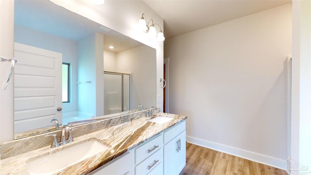 720 Brambling Ct, Cantonment, FL 32533 - bathroom featuring a shower stall, wood finished floors, double vanity, baseboards, and a garden tub