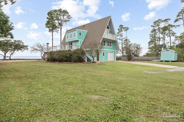 view of front facade with a garage, a front yard, a storage unit, and a balcony