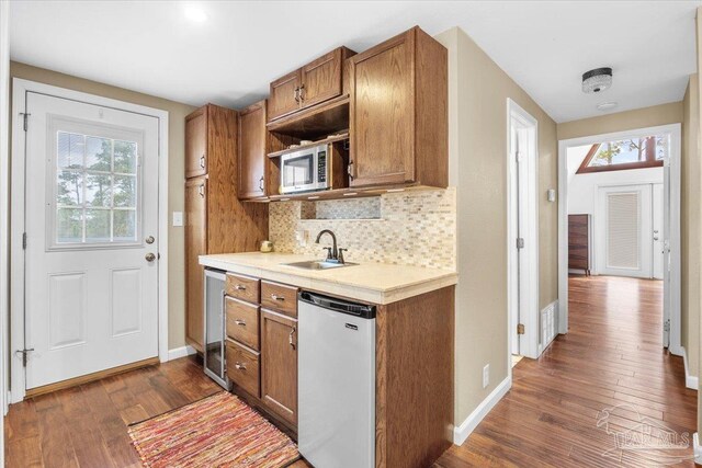 kitchen with dark wood-type flooring, tasteful backsplash, sink, and stainless steel appliances