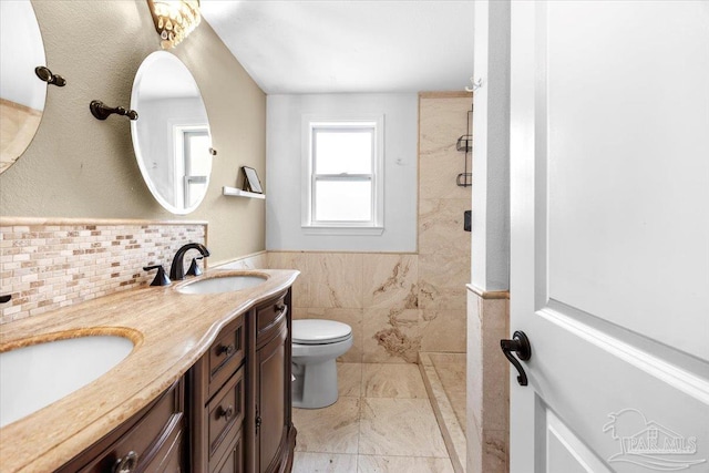 bathroom featuring toilet, vanity, and a tile shower