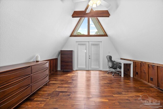 home office with french doors, dark hardwood / wood-style floors, wood walls, lofted ceiling, and ceiling fan