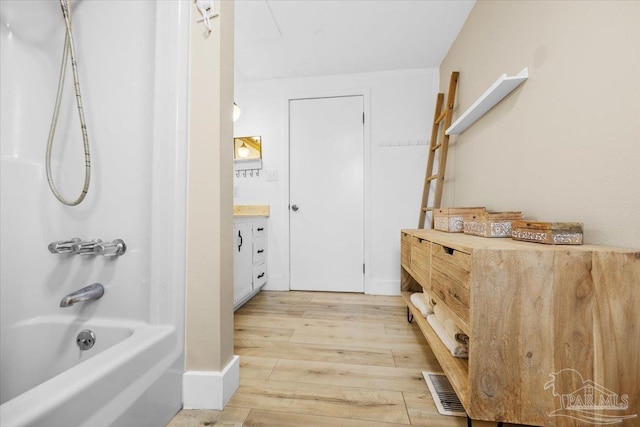 bathroom featuring washtub / shower combination, hardwood / wood-style flooring, and vanity