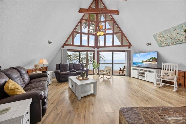 living room with high vaulted ceiling, plenty of natural light, and light hardwood / wood-style floors