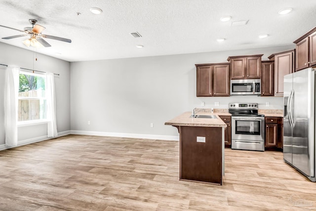 6004 Royal Port Ct, Pensacola, FL 32526 - kitchen with stainless steel appliances, a peninsula, ceiling fan, light wood-style floors, and a textured ceiling